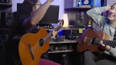 İki gülümseyen müzisyen rahat bir stüdyoda akustik gitar çalmaktan zevk alarak neşeli ve rahat bir müzik ortamı yaratıyorlar..