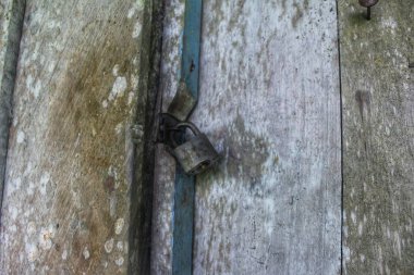 Demirden yapılmış eski bir asma kilitle kilitlenmiş bir kapı.