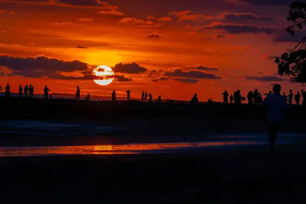 İnsanlar gün batımında sahilde.
