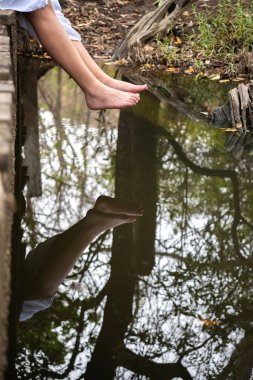 Sakin Orman Suyu 'nun üzerinde sallanan Ayaklarla Huzurlu Anlar