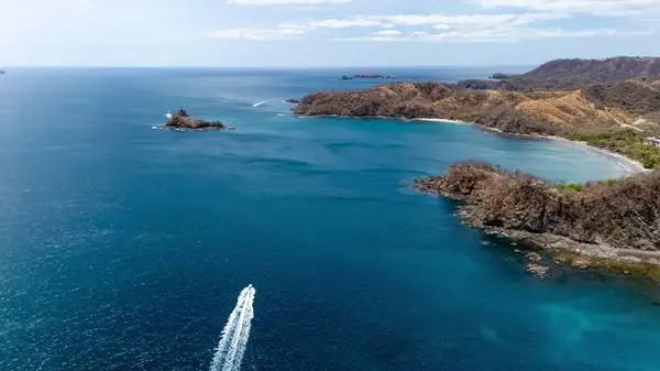 İHA 'lar turkuaz körfezin üzerinde uçuyor. Kayalık kayalıklar ve tropikal kıyı şeridi var..