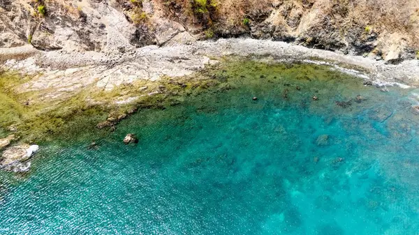 Turkuaz okyanusun havadan görünüşü kayalık kıyı şeridiyle buluşuyor.