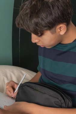 Genç bir adam kalemle deftere yazıyor.