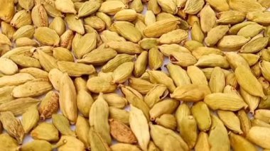 Yeşil kakule kapsülleri tam kare arka plan, mikro çekim, dönme, şifalı otlar ve baharatlar üzerine düşer.