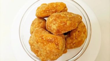 Camdaki organik jaggery ya da Gur parçaları temiz beyaz arka plan, üst manzara, izole edilmiş. Cam kasede kahverengi kamış şekeri parçaları izole edilmiş.