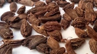 Büyük kakule ya da siyah kakule tam kare arka plan, mikro çekim, dönme, şifalı otlar ve baharatlar üzerine düşer