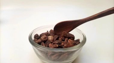 Büyük kakule kaşığı ya da cam kasedeki siyah kakule, tahta kaşık, otlar ve baharatlarla..