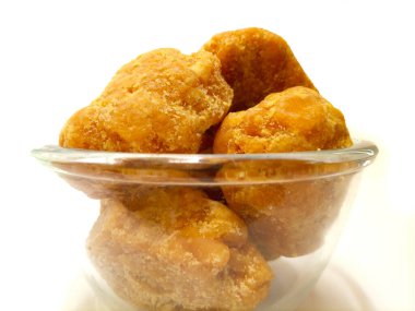 Camdaki organik jaggery ya da Gur parçaları temiz beyaz arka plan, izole yakın plan. Cam kasede kahverengi kamış şeker parçaları izole, ön manzara