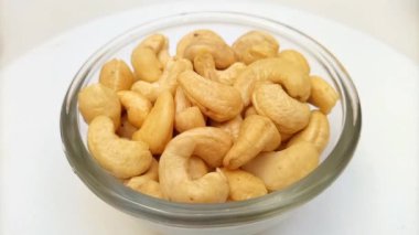 Cam bir kasede kabuksuz kaju fıstığı, döner, kapat. Beyaz arka planda kaju fıstığı. Çiğ çerez. Kurutulmuş fındık. Yakın çekim.