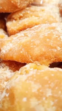 Jaggery ya da Gur parçaları arka planda dönüyor. Organik kahverengi kamış şeker parçaları dikey olarak yakın çekim