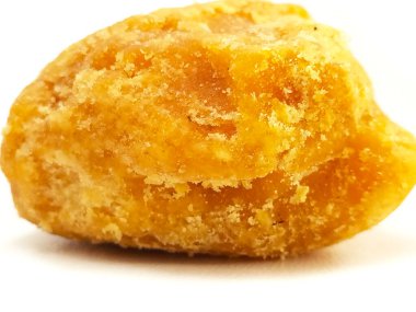 Beyaz arka planda izole edilmiş bir parça Jaggery ya da Gur, mikro çekim. Organik kahverengi kamış şeker parçası izole edildi