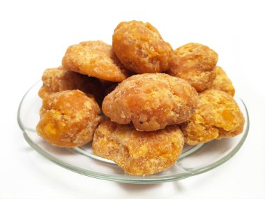 Cam bir plaka içindeki Jaggery veya Gur parçaları temiz beyaz bir arka plana karşı, izole edilmiş yakın plan. Cam tabaktaki organik kahverengi şeker parçaları izole edilmiş.