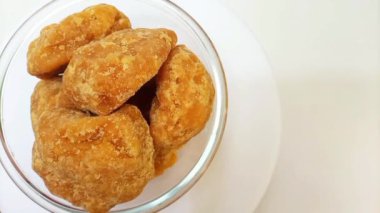 Camdaki organik jaggery ya da Gur parçaları temiz beyaz arka plan, üst görüntü, yan çerçeve, izole edilmiş. Cam kasede kahverengi kamış şekeri parçaları izole edilmiş.