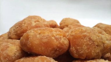 Beyaz arka planda dönen Jaggery ya da Gur parçalarının mikro görüntüsü. Kahverengi organik şeker parçaları.
