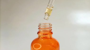 Şişe pipeti damlatıcısını kapat. Sıvı sarı-turuncu C vitamini ya da beyaz arkaplanda retinol serumu.