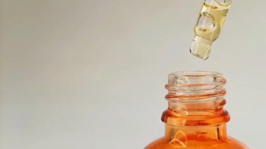 Şişe pipeti damlası sıvısı sarı-turuncu vitamin c veya beyaz arka planda retinol serumu, ekranın sağ tarafında.