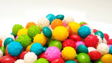 Temiz beyaz arka planda dönen bir yığın karışık renkli tatlı şeker, mikro çekim. Doğum günleri için çok renkli şekerlemeler.