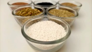 Bir kase dolusu Sago incisine ya da aromatik baharat çeşnili muhallebi incilerine odaklanmak ve cam kaplarda otlar, yakın plan, ön görüş.