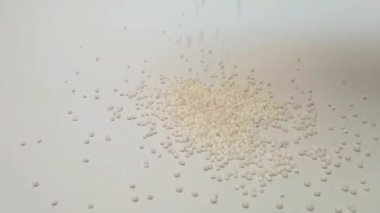 Sago incileri ya da tapyoka incileri orta çerçevedeki temiz beyaz arka plana dökülür, kapak, bitkiler ve baharatlar