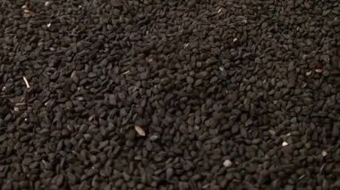 Siyah kimyon tohumları veya siyah kimyon tohumları tam kare arka plan, mikro çekim, dönme, şifalı otlar ve baharatlar üzerine düşer