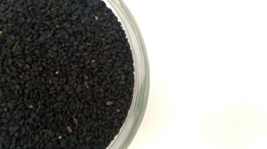 Çemberin yarısı şekilli siyah kimyon tohumları veya çerçevenin sol yarısında siyah kimyon tohumları cam kase, döner, beyaz arka planda izole, yakın plan, bitkiler ve baharatlar