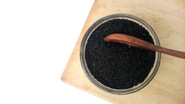 Kara kimyon tohumları ya da cam kaseden tahta kaşık, üst manzara, otlar ve baharatlar alan kimyon tohumları..
