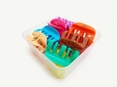 Beyaz arka plandaki bir kutuda renkli plastik saç tokası yığını. Kadın saç aksesuarları. Moda bir aksesuar. Modaya uygun aksesuarlar..