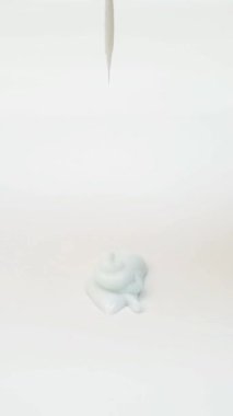 Açık mavi sıvı yüz yıkama, şampuan, temizleyici, kozmetik ya da cilt ürünleri beyaz arka planda, dikey klipste düşüyor..