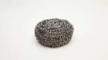 Plastik mutfak eldiveni giyen bir el beyaz bir arka plandan paslanmaz çelik fırça alıyor, temizlik ve yıkama konsepti, metal kap süngeri, fırça tozu