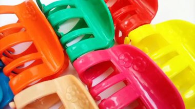 Beyaz arka planda hareket eden renkli plastik saç tokaları. Kadın saç aksesuarları. Moda bir aksesuar. Modaya uygun aksesuarlar.