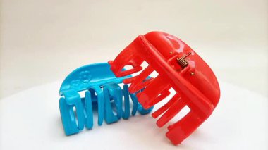 Beyaz arka planda dönen plastik saç tokaları. Kadın saç aksesuarları. Moda bir aksesuar. Modaya uygun aksesuarlar.