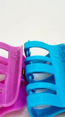 Beyaz arka planda arka arkaya hareket eden renkli plastik saç tokaları. Kadın saç aksesuarları. Moda bir aksesuar. Modaya uygun aksesuarlar. dikey klip.