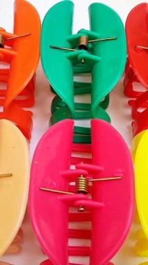 Beyaz arka planda sıra sıra ilerleyen renkli plastik saç tokaları. Kadın saç aksesuarları. Moda bir aksesuar. Modaya uygun aksesuarlar. dikey klip.