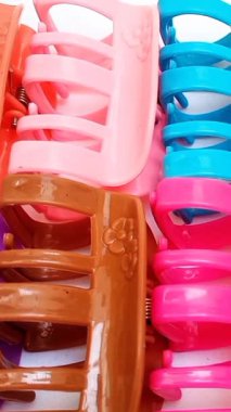Beyaz arka planda hareket eden renkli plastik saç tokaları. Kadın saç aksesuarları. Moda bir aksesuar. Modaya uygun aksesuarlar. dikey klip.