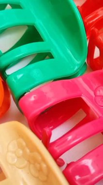  Beyaz arka planda hareket eden renkli plastik saç tokaları. Kadın saç aksesuarları. Moda bir aksesuar. Modaya uygun aksesuarlar. dikey klip.