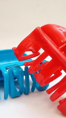 Beyaz arka planda dönen plastik saç tokaları. Kadın saç aksesuarları. Moda bir aksesuar. Modaya uygun aksesuarlar. dikey klip.