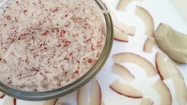 Hindistan cevizi parçalarıyla dolu cam bir kase. Tam kare hindistan cevizi dilimleri. Sol köşede kesikler..