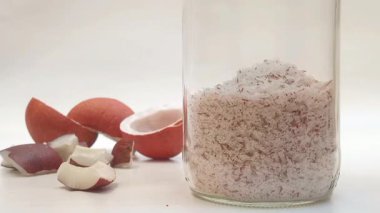 Cam bir kavanoza düşen parçalanmış hindistan cevizi ve beyaz arka planda kalan parçalar.