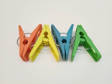 Giysi iğneleri, dört adet çok renkli plastik çamaşır tokası ya da beyaz arka plan için elbise askısı.