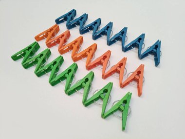 Giysi iğneleri, çok renkli plastik çamaşır tokaları ya da beyaz arka planda elbise askıları.