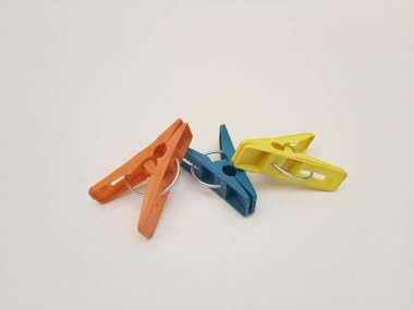 Giysi iğneleri, üç tane çok renkli plastik çamaşır tokası ya da beyaz arka plandaki ev için elbise askısı.