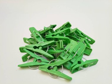 Beyaz arka planda bir yığın yeşil çamaşır tokası, ev için plastik mandallar ya da elbise askıları.