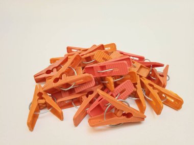 Beyaz arka planda bir yığın turuncu çamaşır tokası, ev için plastik mandallar ya da elbise askıları.