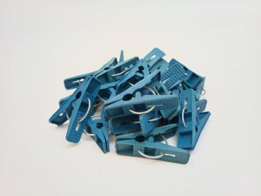 Beyaz arka planda bir yığın mavi çamaşır tokası, ev için plastik mandallar ya da elbise askıları.