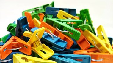 Beyaz arka planda dönen çok renkli plastik çamaşır mandalları, ev için mandallar ya da elbise askıları.