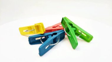 Giysi iğneleri, dört adet çok renkli plastik çamaşır tokası ya da beyaz arka planda dönen ev için elbise askısı.