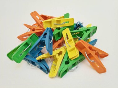 Beyaz arka planda bir yığın çok renkli çamaşır tokası, ev için plastik mandallar ya da elbise askıları.