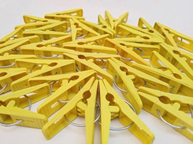 Beyaz arka planda birçok sarı çamaşır klipsleri, ev için plastik mandallar ya da elbise askıları.