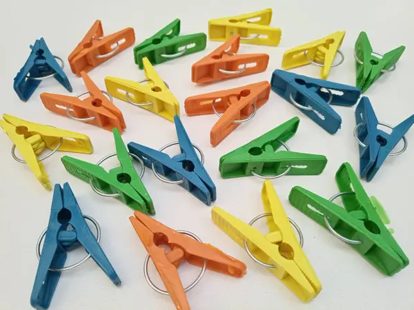 Beyaz arka planda çok renkli çamaşır klipsleri, ev için plastik mandallar veya elbise askıları.