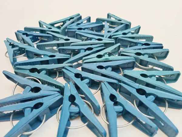 Beyaz arka planda birçok mavi çamaşır klipsleri, ev için plastik mandallar veya elbise askıları.